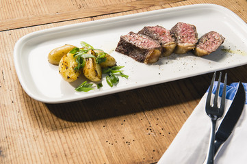 beef and potatoes on white plate with silverware