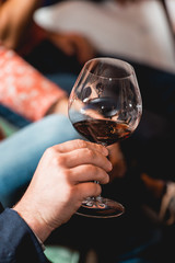 man holds glass of red wine. people consider the color of the wine and try how it smells in different glasses
