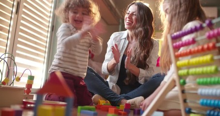 Excited children and babysitter playing with toys on the floor - Powered by Adobe
