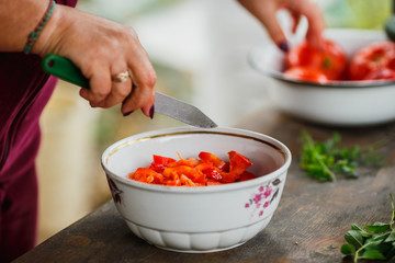 the cooking process for fresh vegetable salad,  healthy nutrition, women's hands cut cucumbers and tomatoes