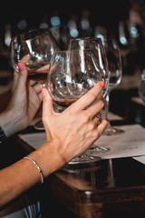 woman holds glass of red wine. people consider the color of the wine and try how it smells in different glasses