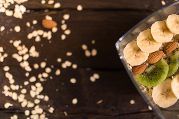 proper nutrition, fitness food, water, fruit, green apple, banana, orange, nuts, wheat. program of diet, dumbbells. The concept of healthy food on a dark wooden background for advertising your text