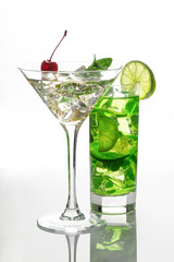 two glasses with soft drinks with ice stand on the white reflecting surface
