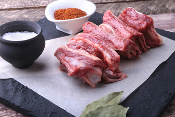 Raw fresh meat, uncooked lamb or beef ribs with pepper, garlic, salt and spices on dark stone background, Ready for cooking. copy space.