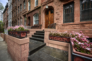 A view of a historic brownstone on a sunny summer day in an iconic neighborhood of Manhattan, New York City.