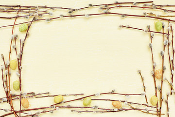 Easter background. Willow branch and decorative Easter eggs on yellow background. Top view, copy space