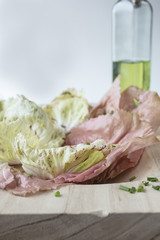 A pink and green radicchio salad in a wood bowl and garnished with chives and olive oil