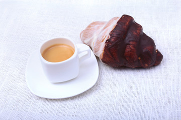 Classic espresso in white cup and croissant on white background. Top view.