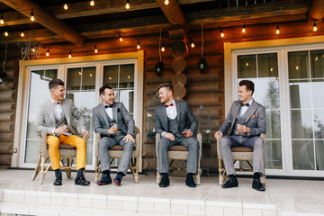 groom with fashionable friends sit on the terrace of the house and talk