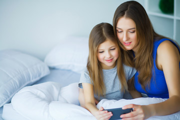 Mother and daughter listening to music in bed