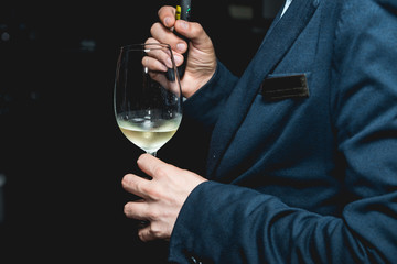 man holds glass of wine. people consider the color of the wine and try how it smells in different glasses