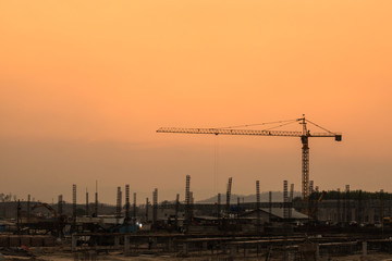 silhouette crane with worker at the construction site along with the evening sun