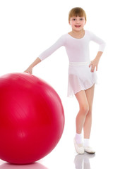 little girl doing exercises on a big ball for fitness.