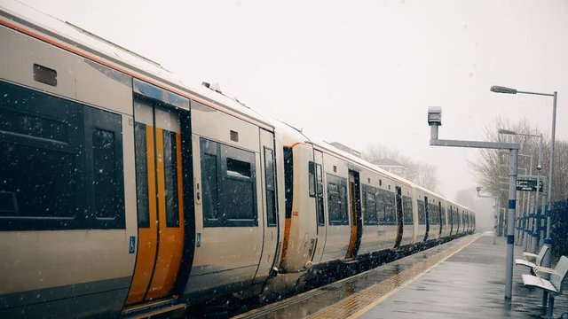 Snowfall. View of the train on the station platform.