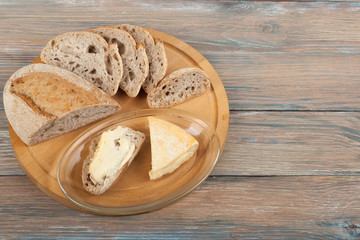 Many mixed breads and rolls of baked bread on wooden table background.