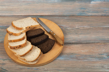 Many mixed breads and rolls of baked bread on wooden table background.
