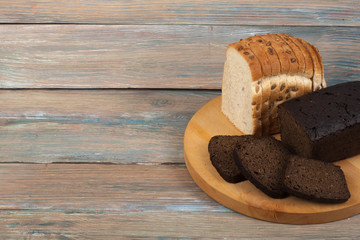Many mixed breads and rolls of baked bread on wooden table background.