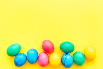 Colorful easter eggs on yellow background top view mock-up