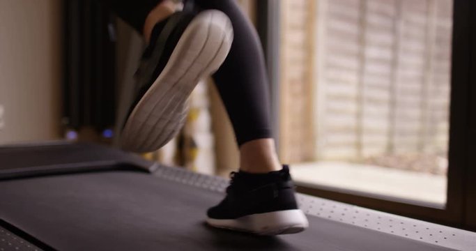 4K Close up on feet of unrecognizable woman working out on running machine. Slow motion.