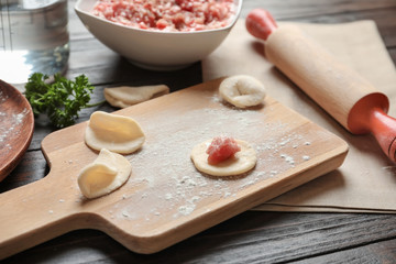 Fototapeta na wymiar Raw dough with minced meat for dumpling on wooden board