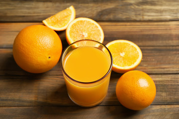 Glass of orange juice and fresh fruits on wooden background