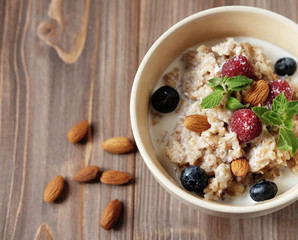 Oatmeal porridge in bowl topped with fresh blueberries and raspb