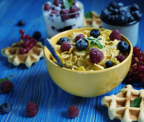 Healthy breakfast with corn flakes, berries, waffle and milk on