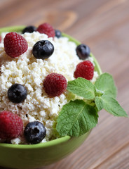 Cottage cheese in green bowl with raspberries  and blueberries o