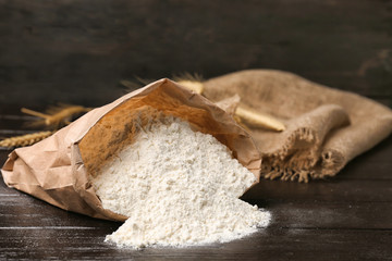 Paper bag with flour on wooden table