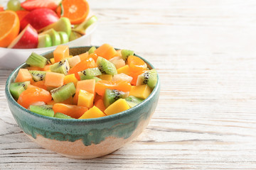 Bowl with fresh cut fruits on wooden table