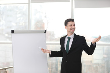 Business trainer giving presentation on flip chart board indoors