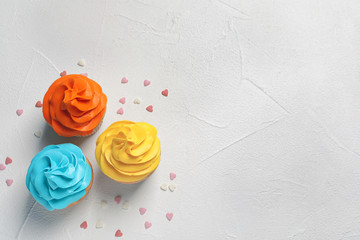Delicious birthday cupcakes on light background