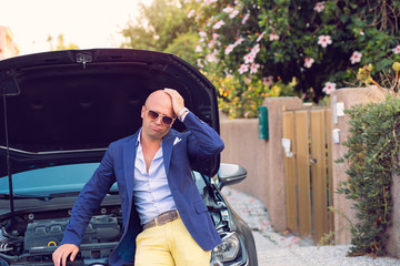 stressed man with broken car looking at failed engine