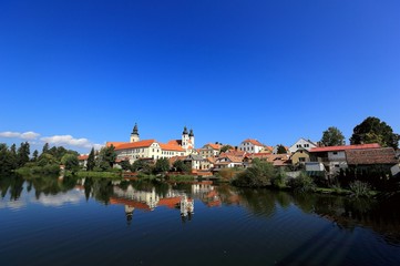 Fototapeta na wymiar A fairy tale castle and old town with beautiful mirror reflections on smooth lake water under clear blue sky in Telc, a UNESCO world heritage site in Czech Republic, Europe 