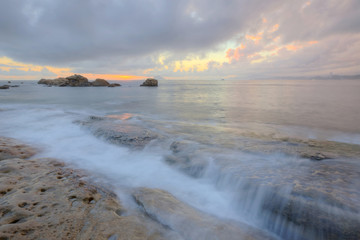 Obraz premium Beautiful rocky beach illuminated by the golden rays of morning sunlight at Yehliu Coast, Taipei, Taiwan ~ A romantic sunrise scenery of Yehliu Geopark with dramatic dawning sky (Long Exposure)