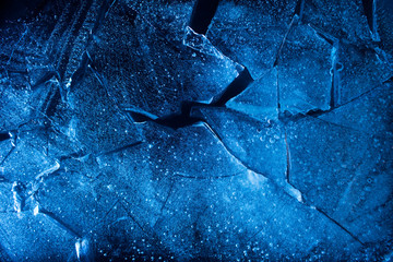Photo texture of a broken blue lightened and toned ice with cracks.