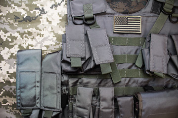 Upper view photo of tactical military bulletproof vest with american flag badge laying on...
