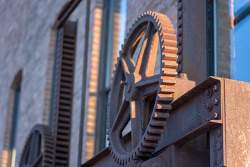 old rusty steel gears outside brick industrial warehouse