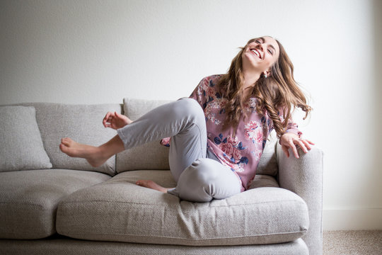 Happy Young Woman Relaxing At Home On Couch