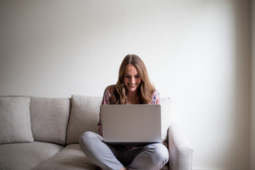 Woman using a laptop at home on couch