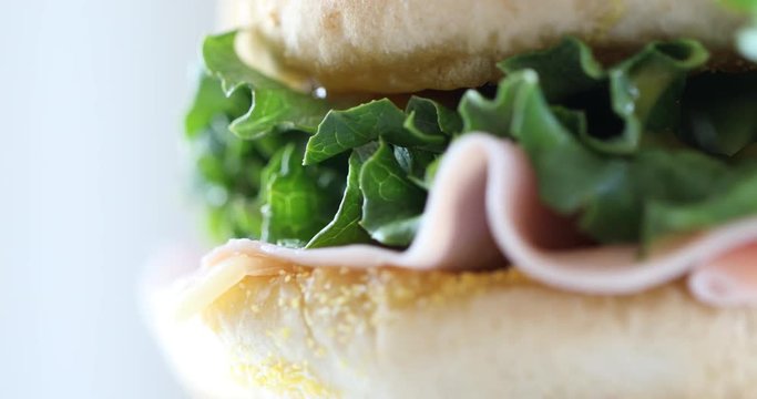 Sandwich on white background. Macro closeup view of rotating sandwich with bun lettuce, cheese and ham. Hamburger 4K footage for web site landing page background.