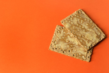 Close-up of rye crackers with butter - on bright orange background - minimal- copy space