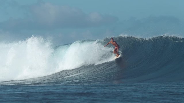 SLOW MOTION: Awesome surfer carves a large breaking ocean wave on a warm sunny afternoon in the summer. Cool extreme rider surfs huge turquoise crashing wave near popular surf spot in Fiji Islands.