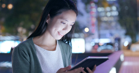 Woman holding tablet computer in city at night