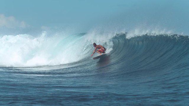 SLOW MOTION: Experienced surfer rides a big barrel wave on popular surf spot. Awesome male surfboarder carves a big deep blue wave coming from the powerful ocean. Adrenaline filled summer activity.