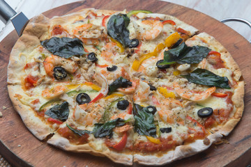 Big tasty pizza with seafood shrimp on a wooden table
