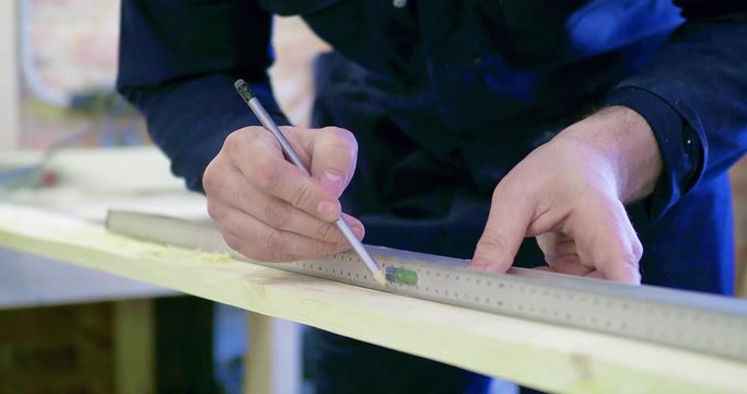 a worker in a carpentry workshop marks the board with a pencil. close-up