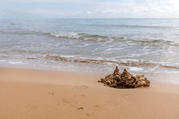 Small sand castle against sea