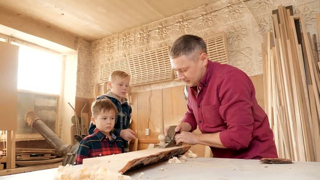 family, carpentry, woodwork and people concept. father teaches son carpentry.