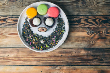 Tea with rose-petals and macaroons on a wooden table. Vintage composition. Top view